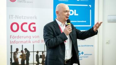 Harald Leitenmüller, CTO von Microsoft Österreich, hält in der OCG einen Vortrag, im Hintergrund Roll-ups mit Informationen zur OCG und zum ICDL/ECDL